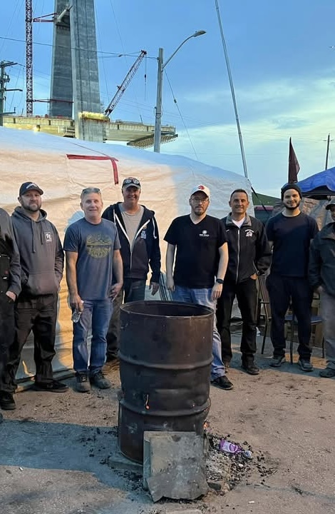 Members standing near a picket fire barrel