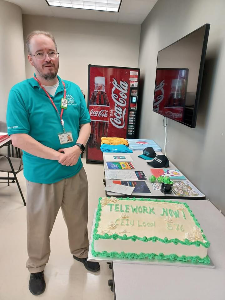Member beside Telework Now table and cake